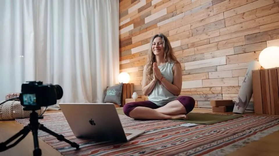 Yogalehrerin unterrichtet eine Online-Yogastunde am Laptop